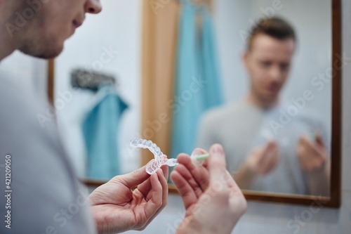 Quadro su tela Young man preparing silicon tray for teeth whitening and bleaching gel syringe