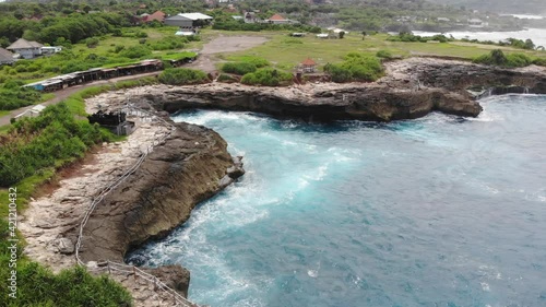 Aerial top view 4k footage by drone of ocean blue waves break on high cliff of a rocky mountain. Danger sea waves on a beach