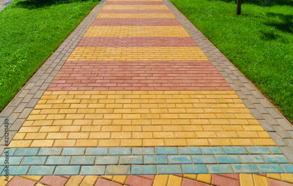 Obraz premium walkway made of paving slabs and green grass as a background, bright sunlight