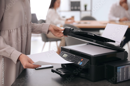 Employee using modern printer in office, closeup photo