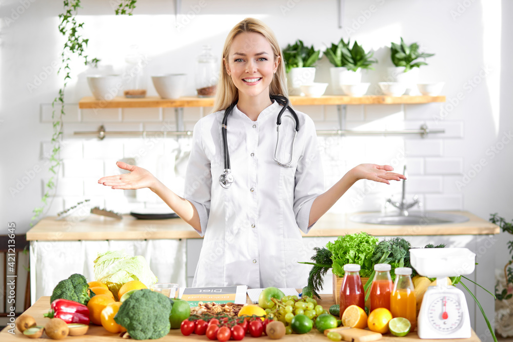 Professional dietitian in medical suit posing at camera, healthy food vegetables and fruits on table Professional dietitian in medical suit posing at camera, healthy food vegetables and fruits on table