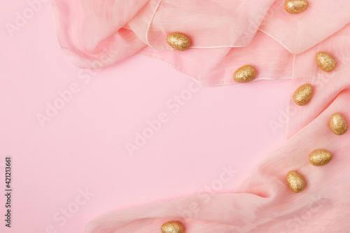 Minimal layout golden Easter eggs on a pink fabric background with copy space.