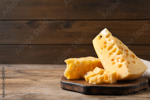 Pieces of delicious cheese on wooden table, space for text