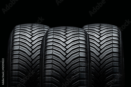 three summer tires on a black background. Drainage grooves and slats photo