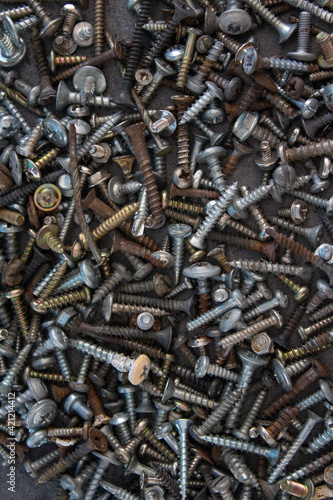 A lot of old rusty nuts and bolts on grey concrete table. Abstract industrial background. 