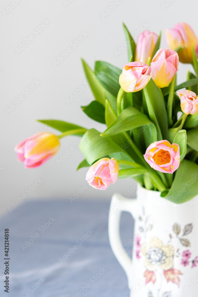Beautiful spring bouquet of pink tulips in a jug on the table, flowers in a home interior Beautiful spring bouquet of pink tulips in a jug on the table, flowers in a home interior