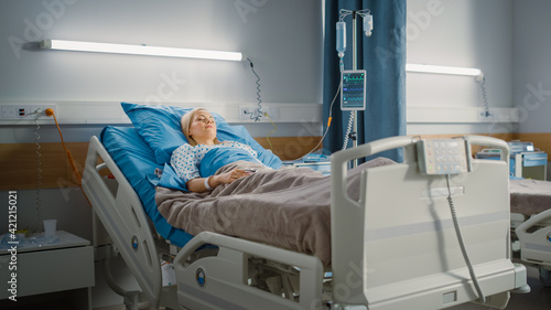 Hospital Ward: Beautiful Caucasian Female Patient Sleeping Peacefully in Bed, Recovering after Successful Surgery. Spaceous Light Room with Window with a Sunny View. Modern Equipment Clinic
