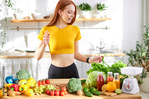 pretty nice woman with lots of healthy fresh food in kitchen. Concept of losing weight, sports and healthy eating