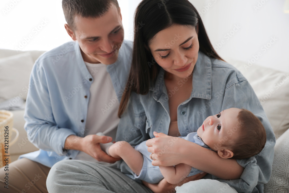 Happy family with cute baby on sofa at home Happy family with cute baby on sofa at home