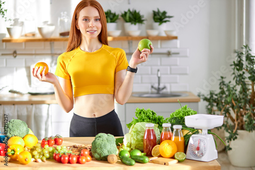 Portrait Of Good-looking Woman Holding Orange And Apple in Hands Talking About It's Benefit