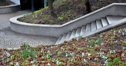 retaining wall at the large staircase in the park the flowerbed area is planted with rich greenery of perennials granite paving of cubes photo