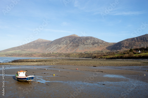 Trefor beach, Wales. Two small fishing boats at a secluded bay near Snowdonia on the Llyn Peninsula on a sunny, bright spring day. Peaceful placid countryside. Landscape aspect. Clear blue sky.