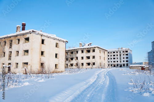 Abandoned apartment buildings in the ghost town Kadykchan, famous for coal mines, Kolyma, Magadan region, during sunny winter day © Lina