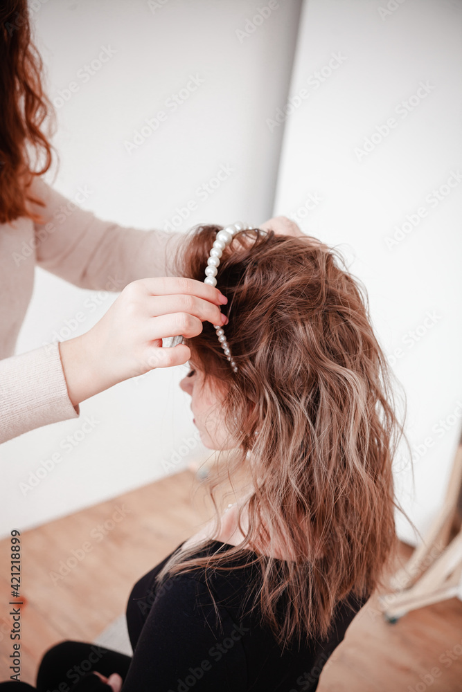 Naklejka premium the hairdresser puts the girl's hair, jewelry made of pearls