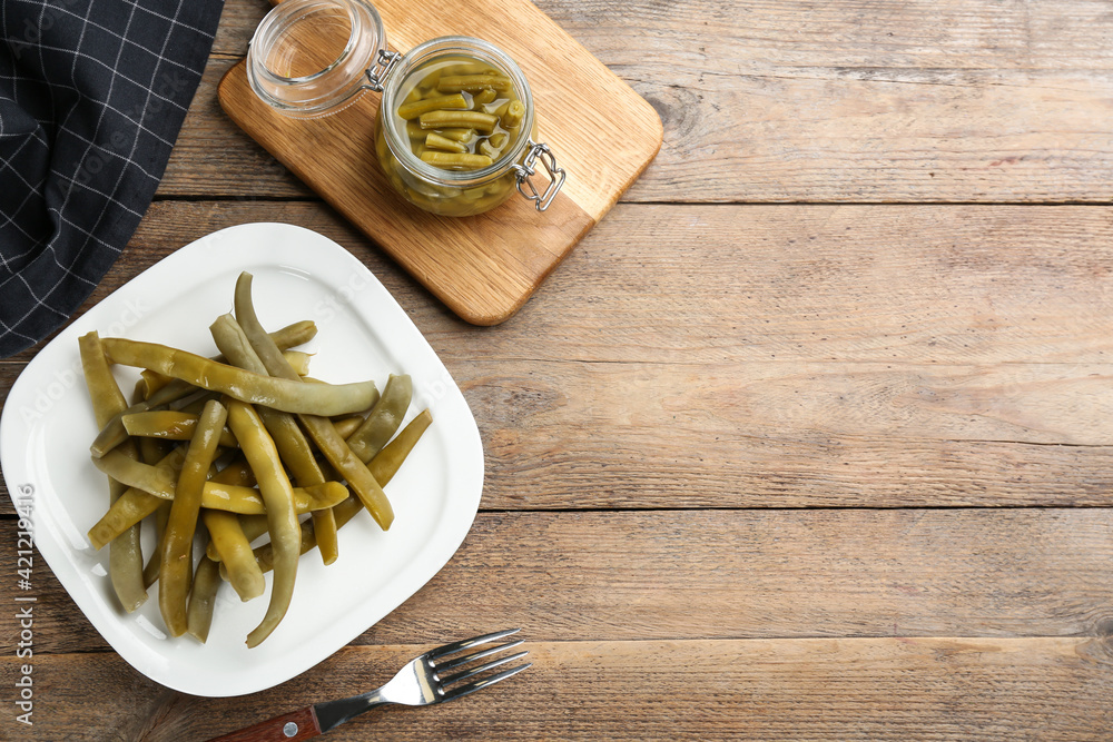 Canned green beans on wooden table, flat lay. Space for text