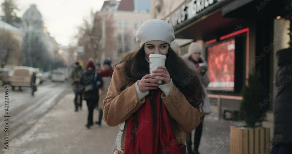 beautiful girl with long curly hair takes coffee and walks in the evening winter city beautiful girl with long curly hair takes coffee and walks in the evening winter city