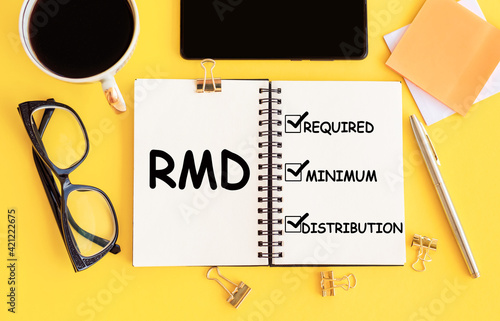 RMD - Required Minimum Distributions, text on notepad and office accessories on yellow desk. photo