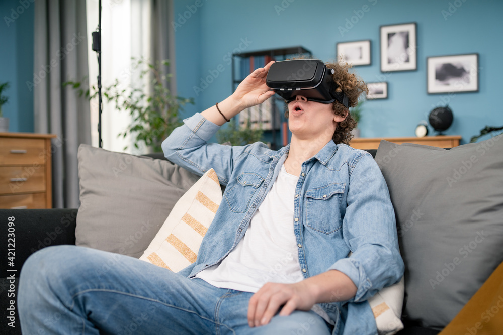 Obraz premium Young man in casual clothes wear the virtual reality glasses is watching and showing imagine via the VR camera, Technology and innovation concept