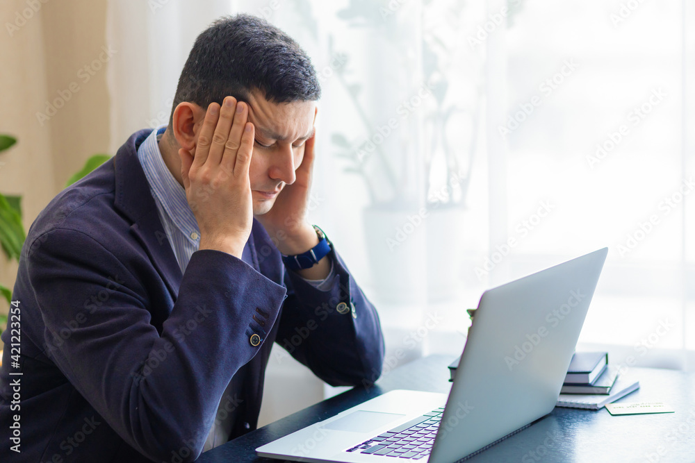 Tired upset businessman, attractive man in suit on workplace for laptop feeling fatigue, stress, headache, migraine due to problems a lot of work, bankruptcy, debts. health of business people. Tired upset businessman, attractive man in suit on workplace for laptop feeling fatigue, stress, headache, migraine due to problems a lot of work, bankruptcy, debts. health of business people.