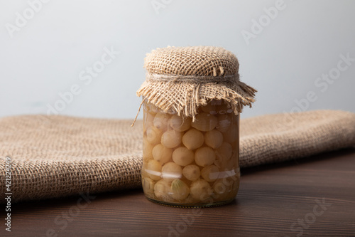 Pickled pearl onions in a glass jar with linen material on top