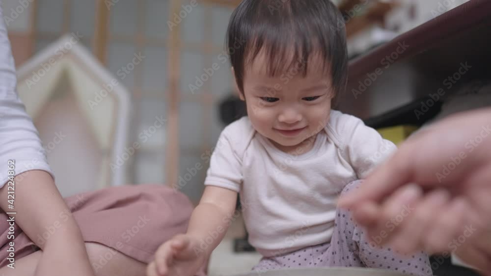 A lovely asian family doing activity together at home on weekend, cute playful toddler interested in playing several and small beads, modern living room in background, new lifestyle of parenthood A lovely asian family doing activity together at home on weekend, cute playful toddler interested in playing several and small beads, modern living room in background, new lifestyle of parenthood