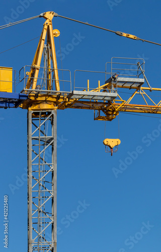 Wallpaper Mural Tower crane vertical column and pulley trolley. Yellow and grey steel structure against blue sky. Machinery or equipment hoist used in construction industry for heavy lifting on building site Torontodigital.ca