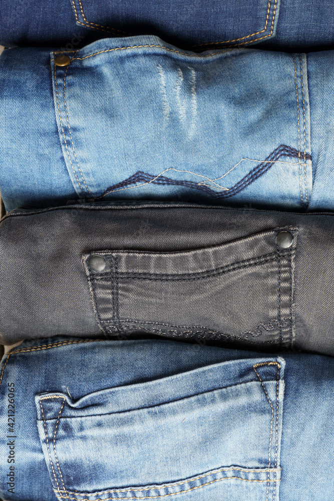 Top view of rolls of various blue jeans. Background from denim pants.