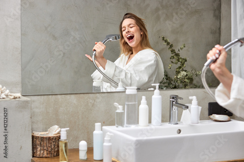 happy woman singing in bathtub using shower head having fun alone, after shower photo