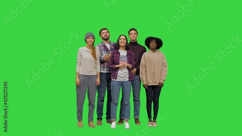 A team of young people listening attentively to someone behind the camera, nodding their heads, getting serious expressions on the faces on a Green Screen, Chroma Key.