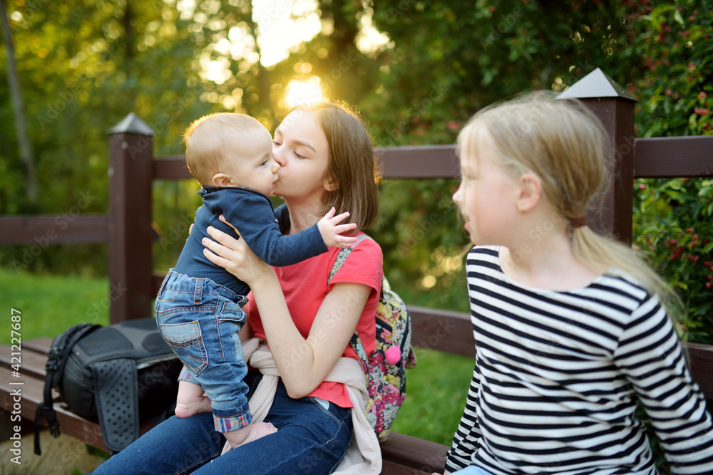 two-big-sisters-and-their-infant-brother-having-fun-outdoors-two-young