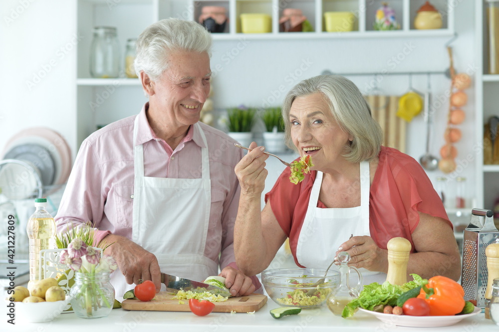 happy senior couple making salad together at kitchen happy senior couple making salad together at kitchen