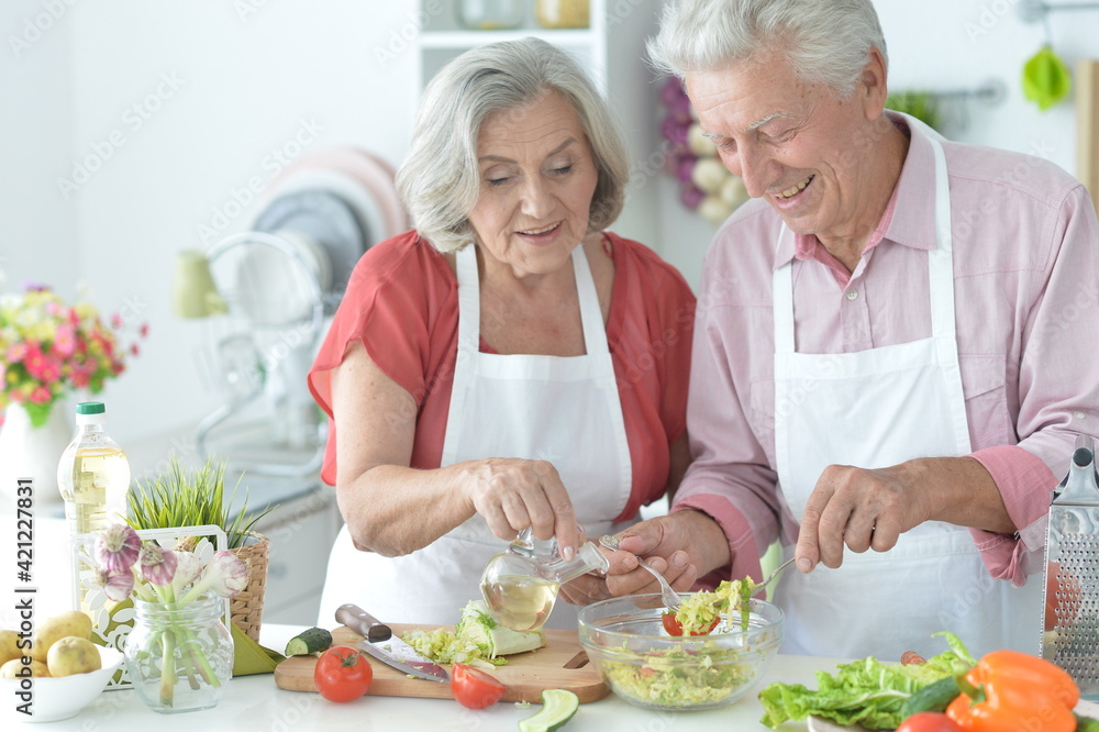 Senior couple making salad together at kitchen