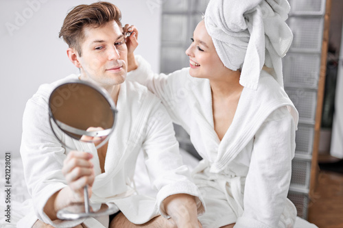 portrait of funny couple doing make-up at home