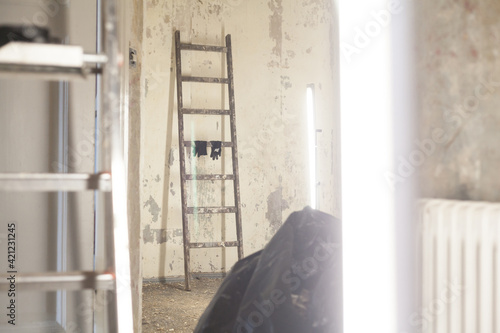 Wallpaper Mural Old wooden ladders and new aluminum ladders with work gloves in front of a bare, unrenovated interior wall without wallpaper. Old radiators calculate heating output. Garbage bags disposal Torontodigital.ca