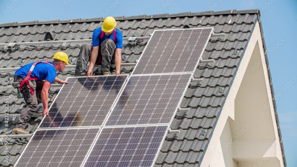 Workers installing alternative energy photovoltaic solar panels on the roof