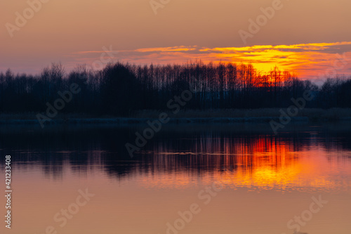 Beautiful sunset over the trees by the water © darekb22