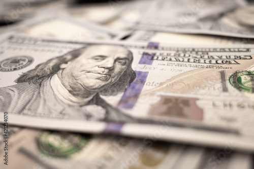 Pile of dollars lies on the table. One hundred dollar bills dumps on table. Background for design from lot of money. Blurred focus. Close-up. Side view