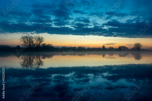 Fototapeta Naklejka Na Ścianę i Meble -  A mirror reflection of the evening clouds in the lake water