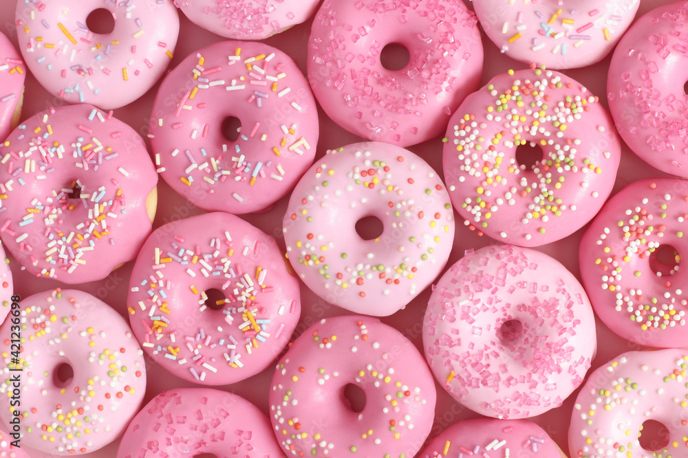 Pink glazed donuts, doughnuts with sprinkles. Sugar, sweets, snack, junk food concept. Top view. Pink glazed donuts, doughnuts with sprinkles. Sugar, sweets, snack, junk food concept. Top view.