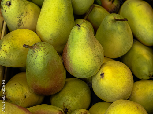 A heap, pile of ripe bright yellow green pears in a store, in a supermarket. Fruits lie on top of each other