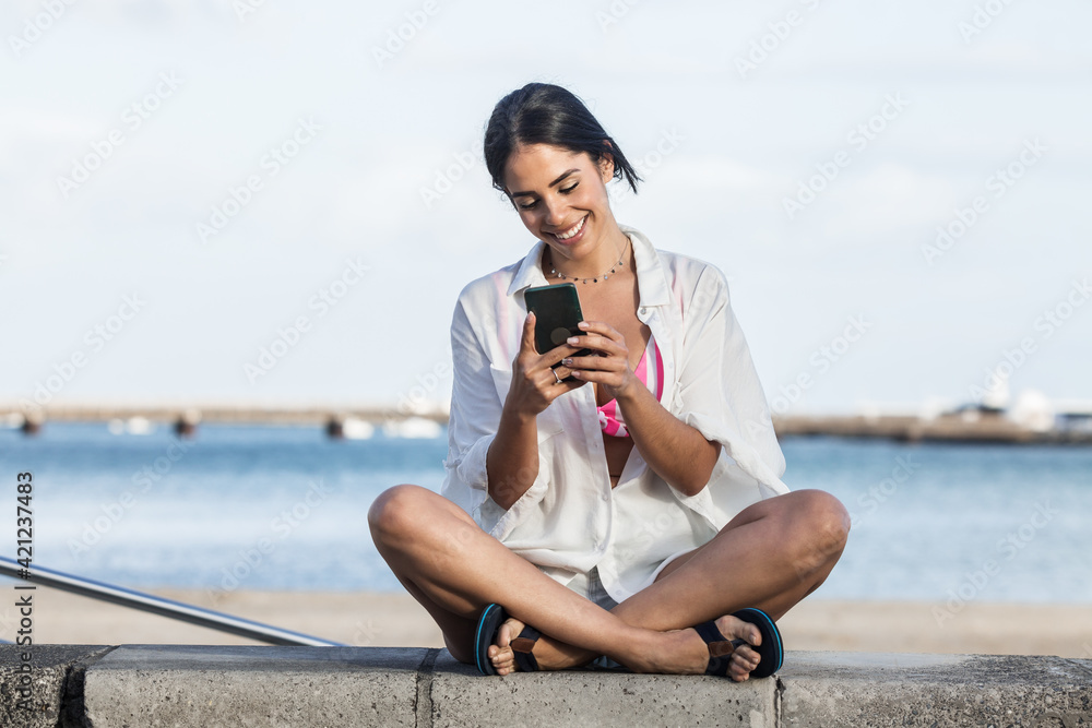 Delighted woman using mobile phone on embankment