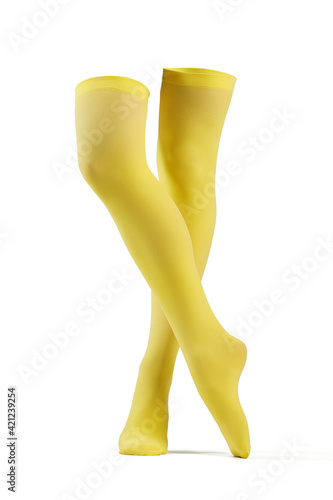 Subject shot of solid yellow opaque stockings without print. The legs are isolated on the white background.
