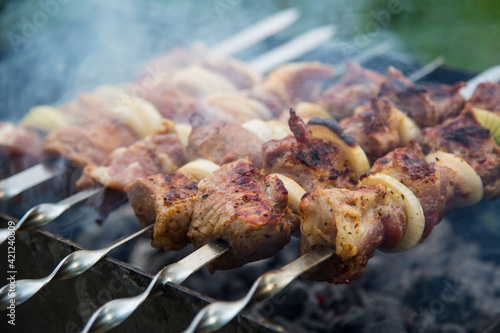 Spits with pieces of meat on the grill over hot coals, close-up top view