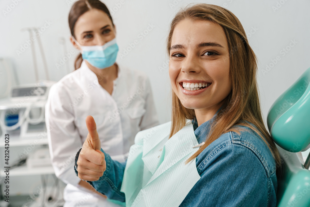 European young woman showing thumb up while sitting in medical chair European young woman showing thumb up while sitting in medical chair