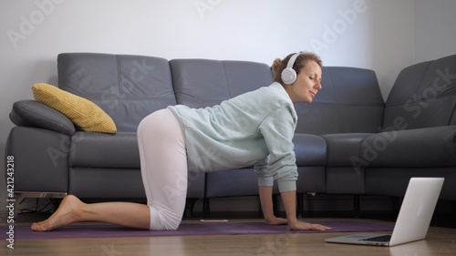 Young Caucasian woman practising yoga online at home. Staying fit during covid-19 pandemic  © Sia