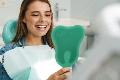 Tableau sur toile European young woman smiling while looking at mirror in dental clinic