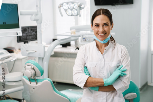 European mid dentist woman smiling while standing in dental clinic