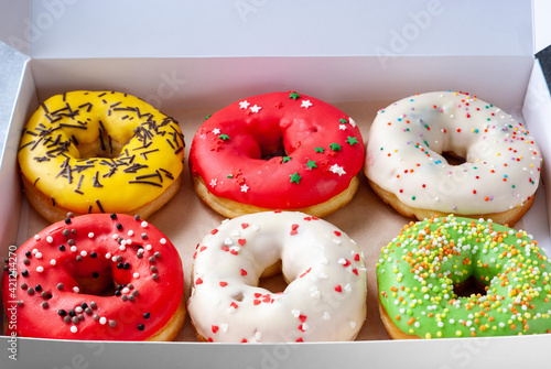 Six assorted glased sweet donuts in a paper box photo