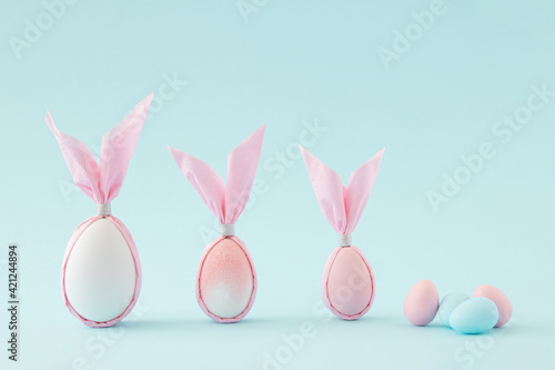Easter pink and white eggs shaped as a bunny against pastel blue color. Creative minimal composition.