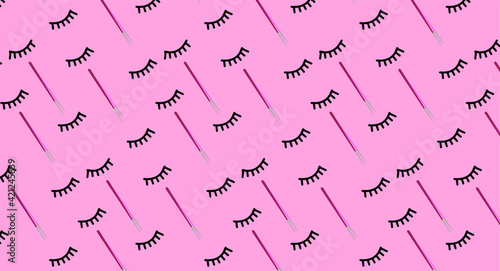 Creative concept beauty photo of lashes extensions brush on pink background.
